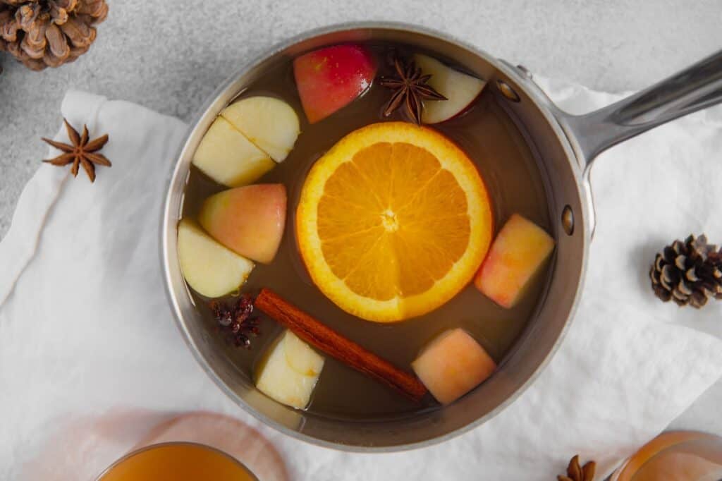 Overhead photo of apple cider with sliced orange and cubed apples in a pot.