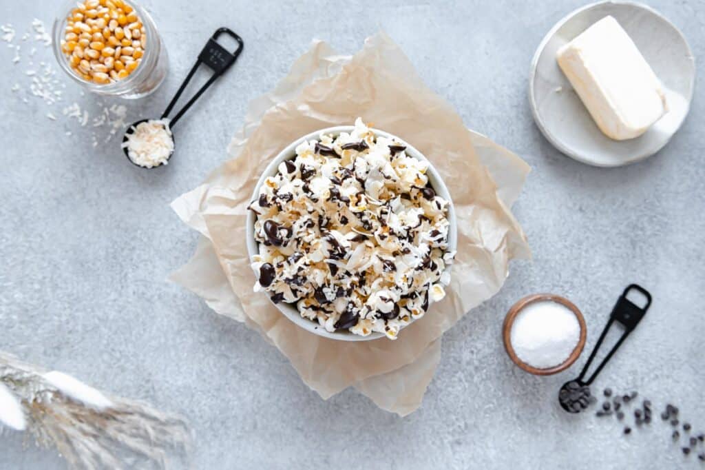 Overhead photo of a popcorn bowl in the center with ingredients laying around the edges.