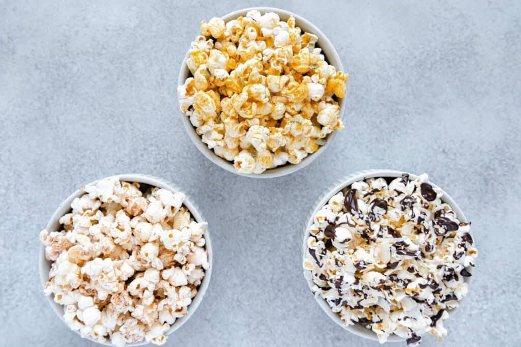 Overhead photo of three different popcorn bowls with popcorn seasoning.