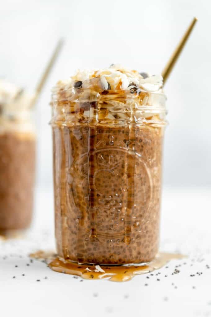 Chocolate chia seed pudding with agave dripping on the sides of the mason jar and onto the countertop.