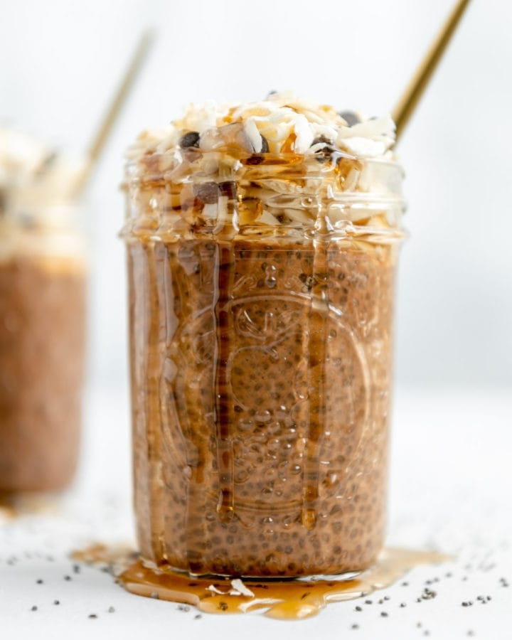 Chocolate chia seed pudding with agave dripping on the sides of the mason jar and onto the countertop.