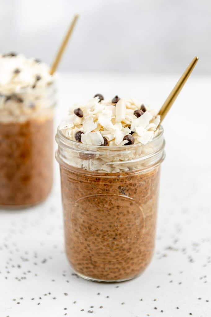 Overnight chocolate chia seed pudding in a mason jar with coconut flakes and chocolate chips on top.