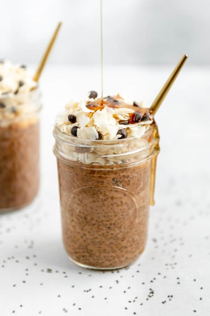 Drizzle shot of agave on top of chocolate chia seed pudding with some agave dripping on the side of the mason jar.