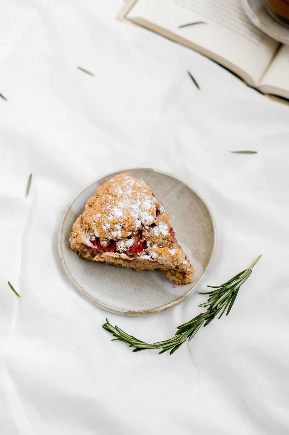 Overhead shot of a slice of vegan strawberry rosemary scone on a plate.