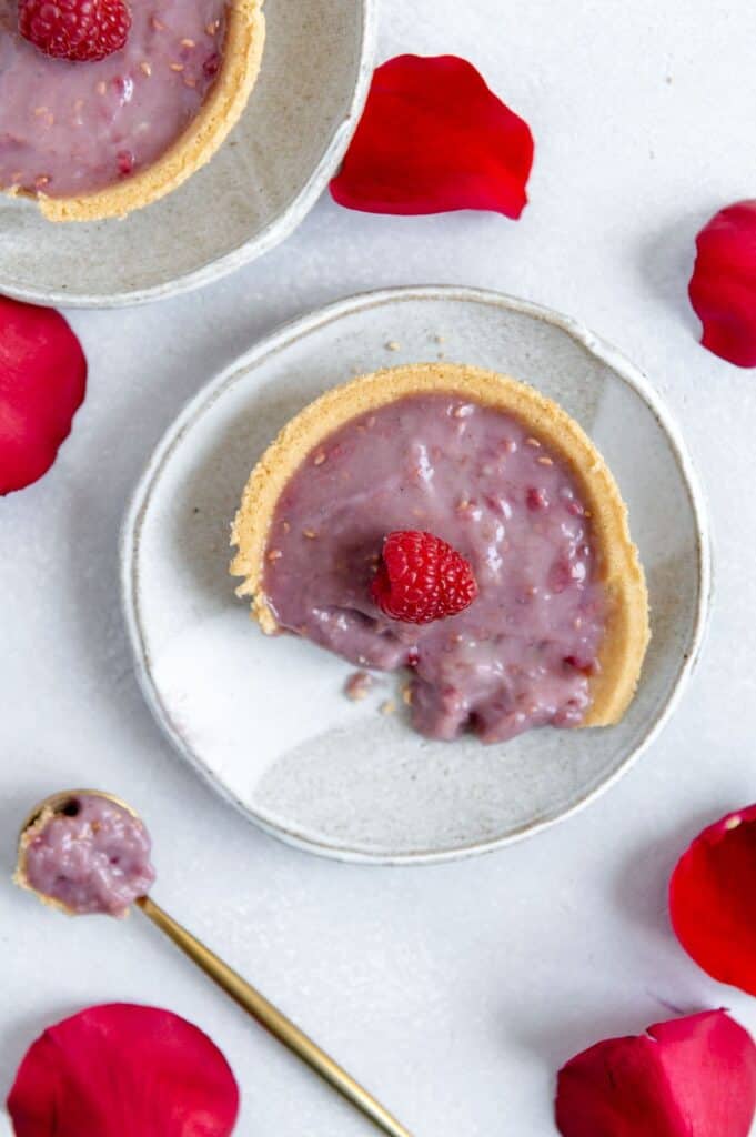 Overhead shot of half eaten raspberry tart on a plate.