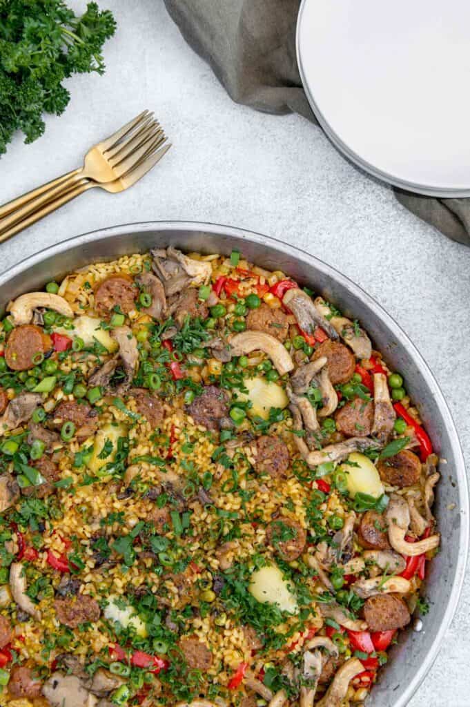 Paella with Beyond Sausage with forks and plates on the side.