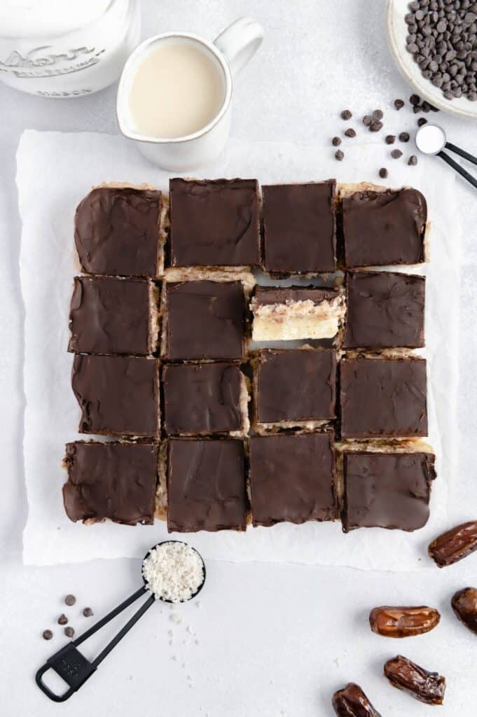 Overhead of 16 squares of vegan millionaire shortbread cookies with one turned up to see the layers.