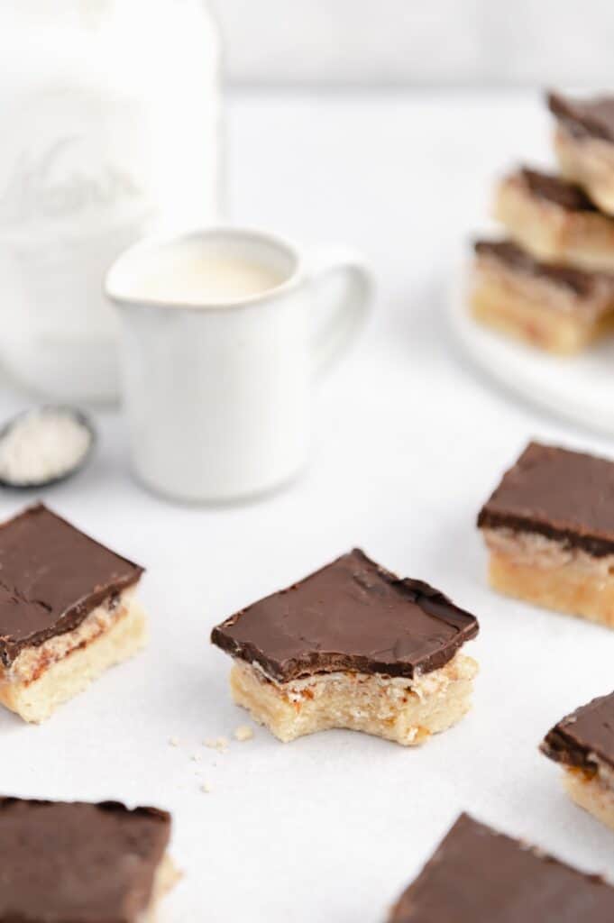 A vegan millionaire shortbread cookie with a bite taken out of it with others scattered around.