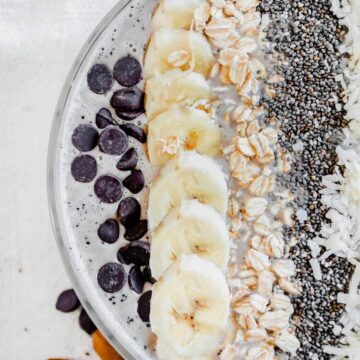 Upclose of a coffee banana smoothie bowl topped with chocolate chips, banana, oats, chia seeds and coconut.