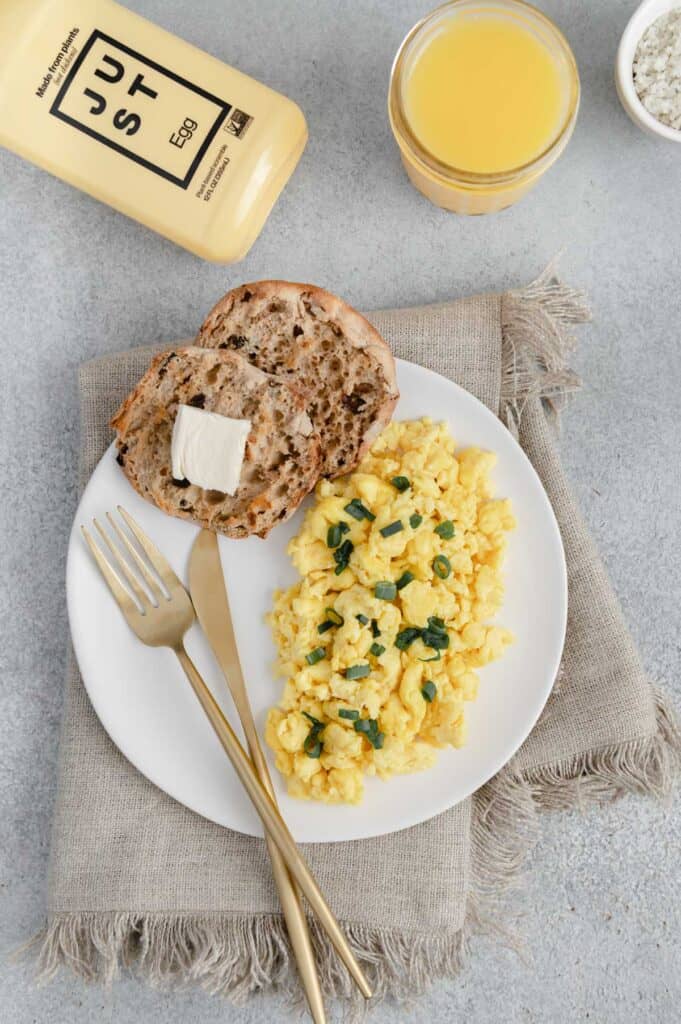 Flatlay of Just Eggs bottle, orange juice and a plate of Just Eggs with an English muffin.