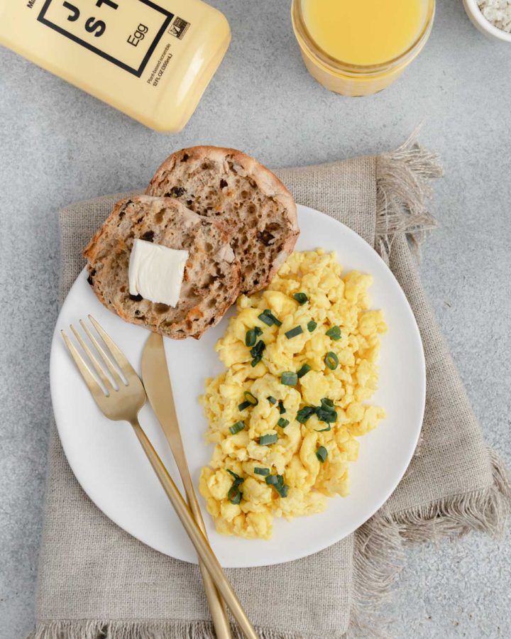 Flatlay of Just Eggs bottle, orange juice and a plate of Just Eggs with an English muffin.