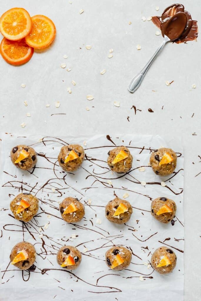 Overhead of 16 no bake cookie dough bites with sliced orange triangles on top.