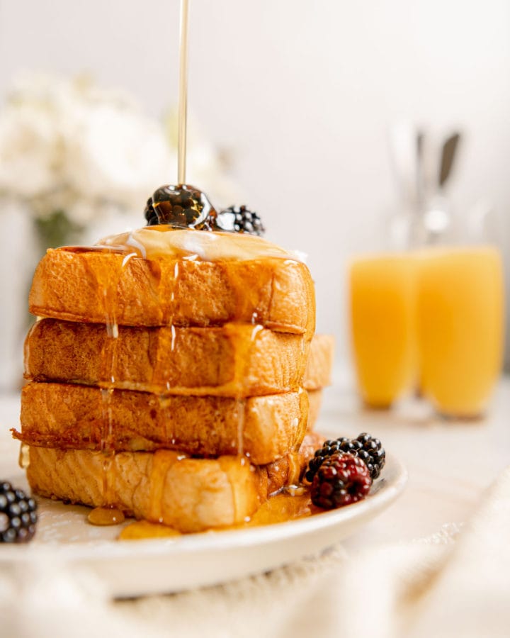 Maple syrup being poured on top of a stack of vegan French toast with Just Egg.