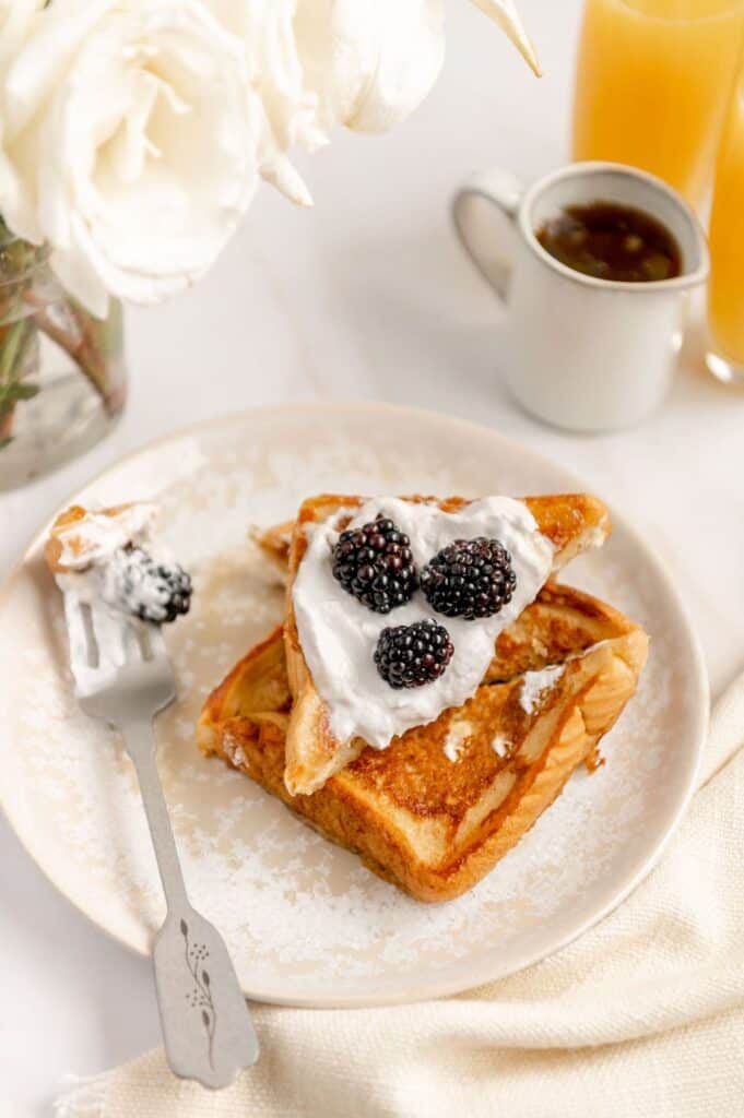 Vegan French toast cut up on a plate and a fork full of French toast waiting to be eaten.