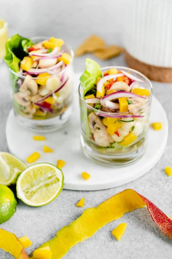 Two cocktail glasses with vegan ceviche on top of a marble serving tray.