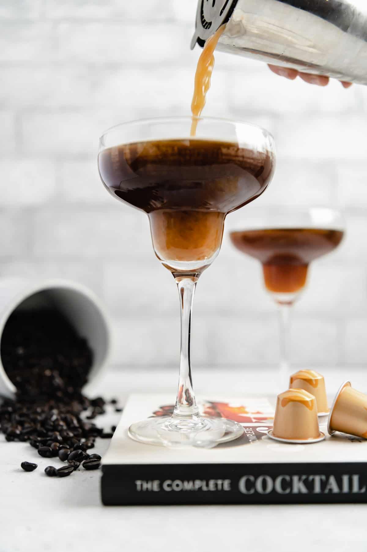 Martini shaker pouring espresso martini into glass.