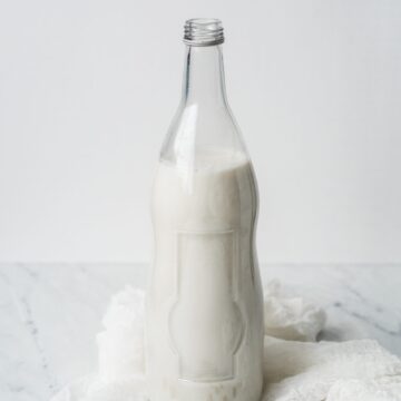 Almond milk in a milk jug on top of cheese cloth.