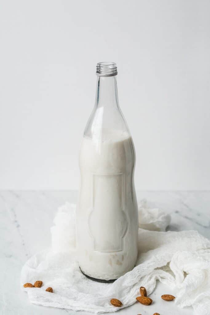 Almond milk in a milk jug on top of cheese cloth.