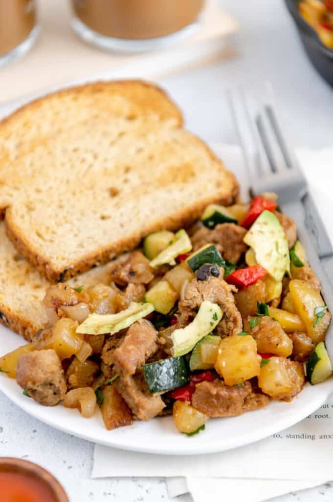 Upclose of a breakfast hash with potatoes, vegetables, avocado, and Beyond Meat sausage.