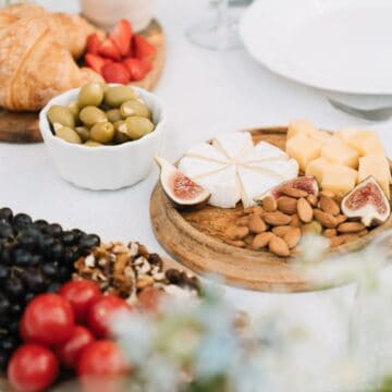 Vegetarian cheese board spread with nuts, cheese, olives, bread, and no meat.