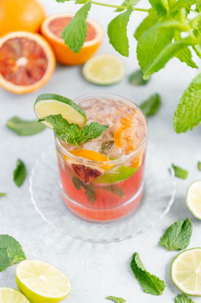 Blood orange cocktail served on a scalloped glass plate.