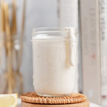 A thick drop of aioli dripping down the side of a mason jar.