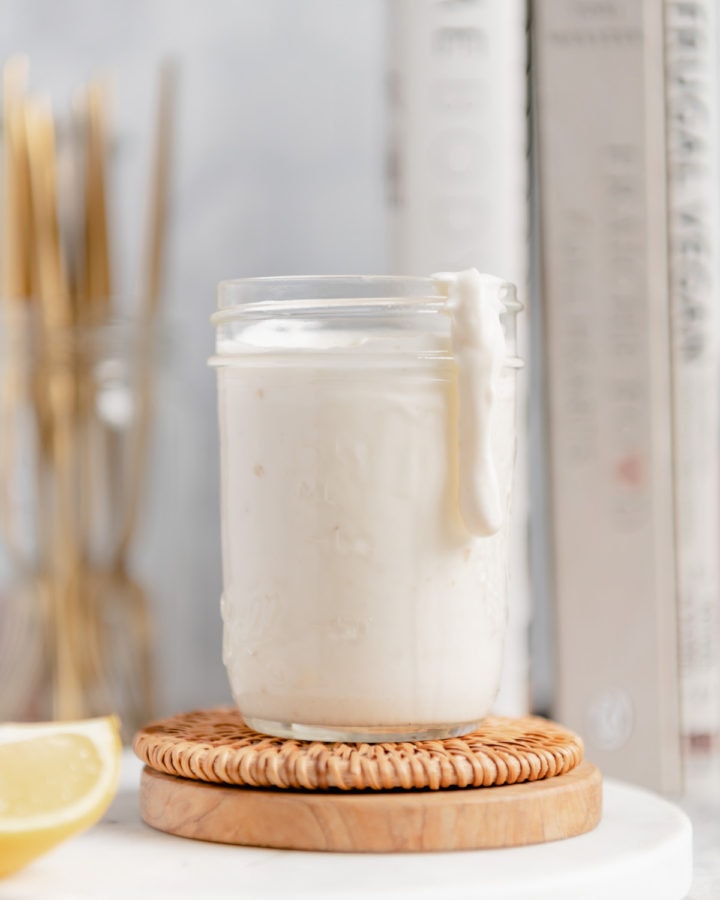 A thick drop of aioli dripping down the side of a mason jar.