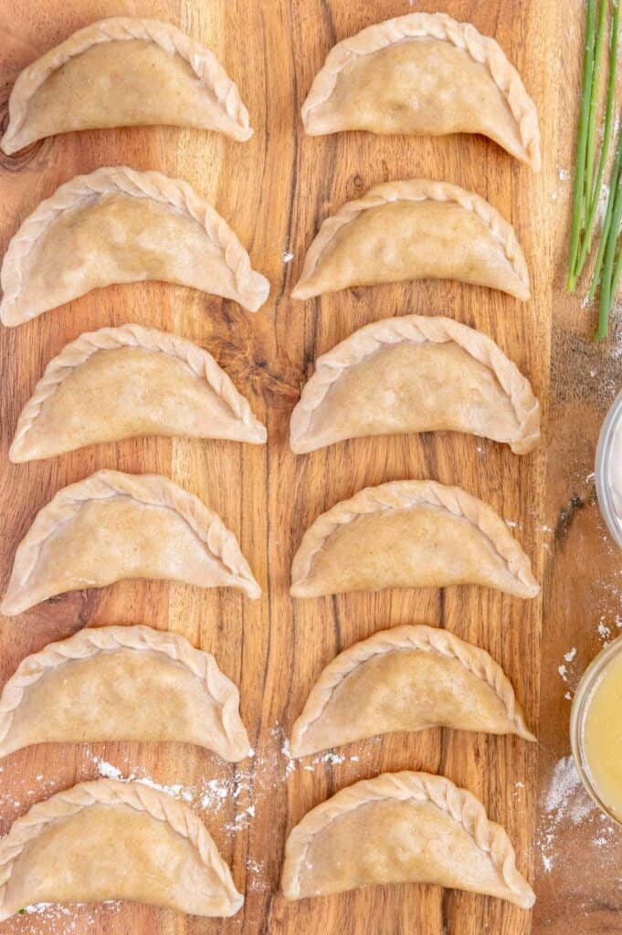Two rows of pierogies on a cutting board.