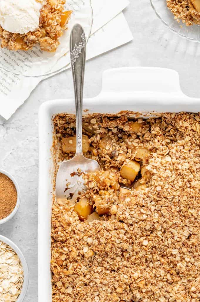 Overhead of a baking dish with an apple crisp with a serving spoon.