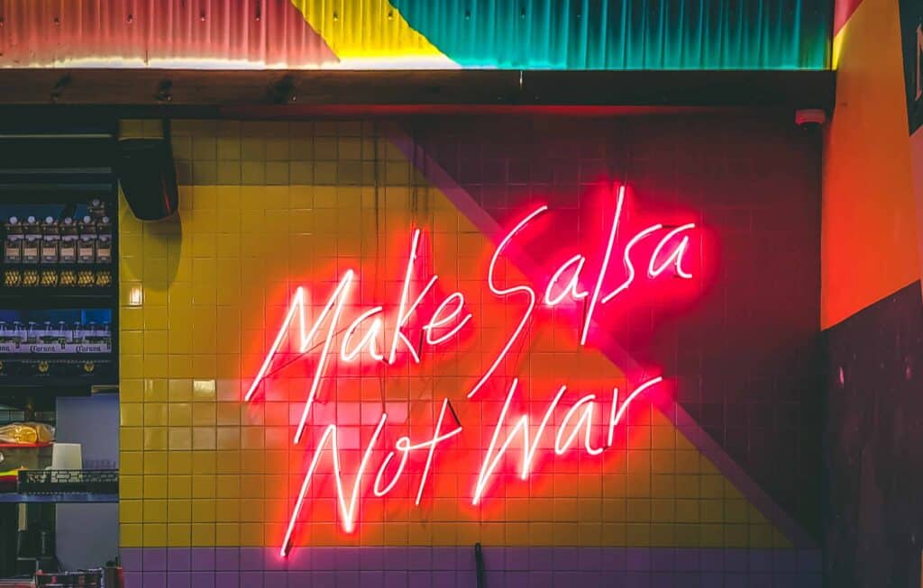 Neon sign that reads "make salsa not war."