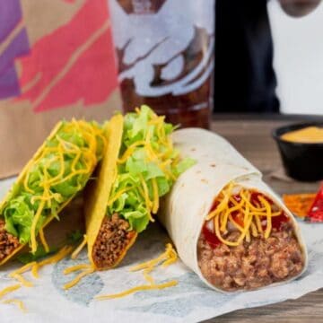 A burrito and crunchy tacos on a picnic table from Taco Bell.