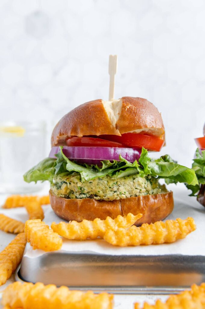 A grilled vegan tofu burger with lettuce, onion, and tomato.