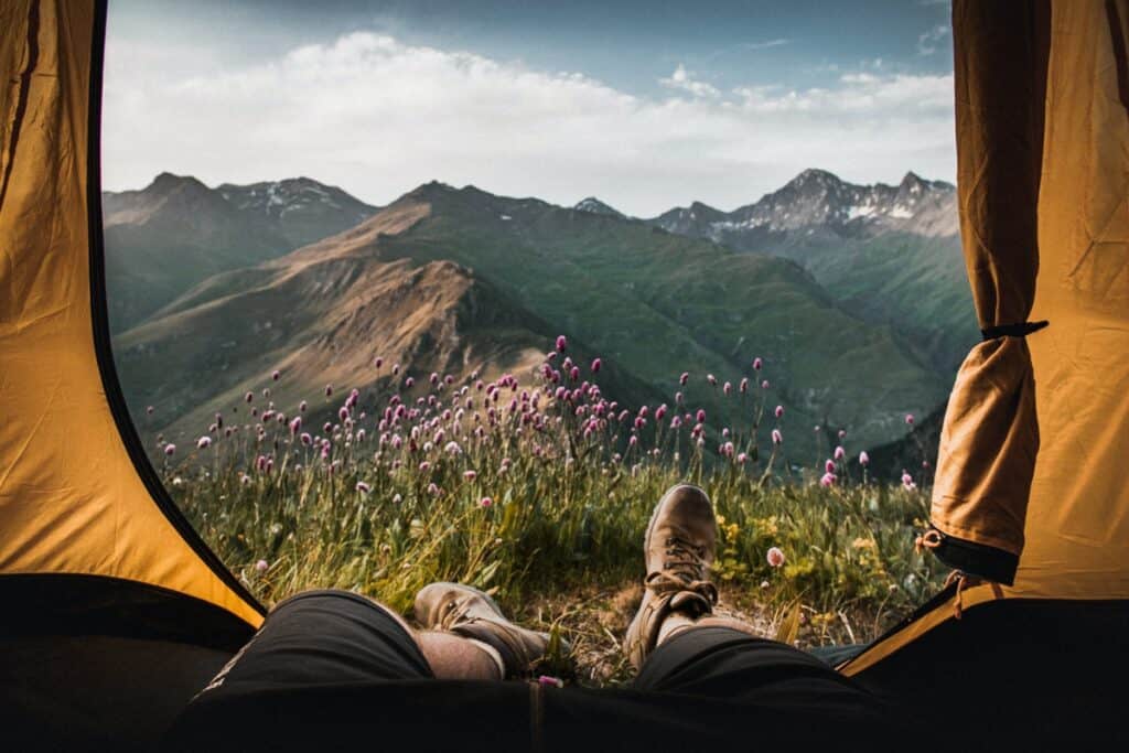 Feet dangling out of a tent looking over a beautiful mountain range.