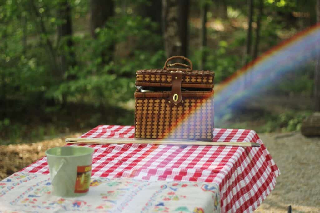 Picnic table with a woven picnic basket and a rainbow.