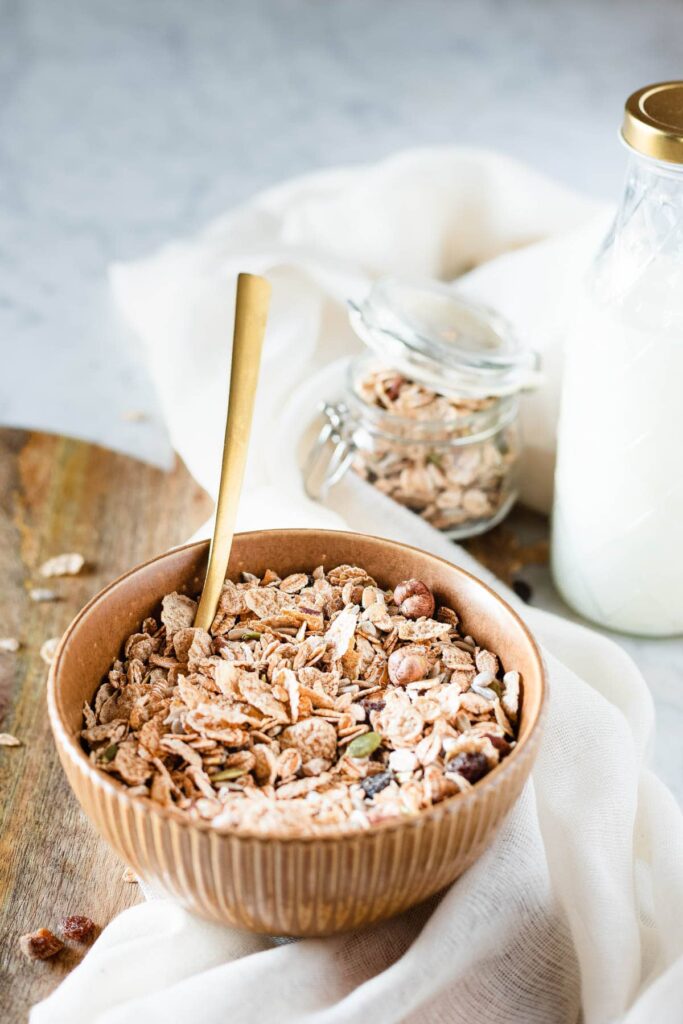 A owl of oats mixed with nuts and milk in the background.