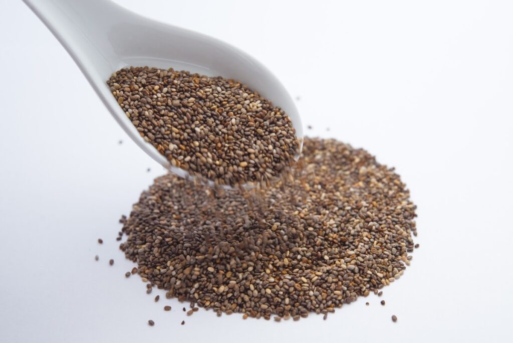 Chia seeds being poured out of a spoon.