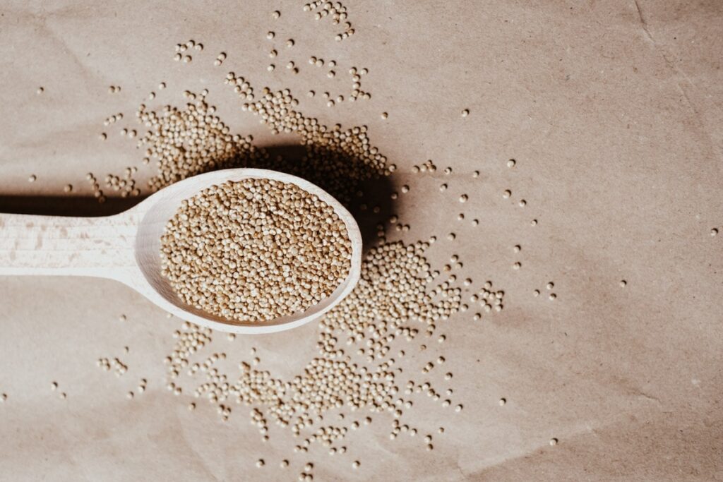 Quinoa in a spoon and scattered around the table.