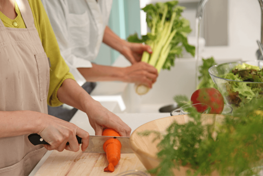 A man and women prepping vegetables in the kitchen.