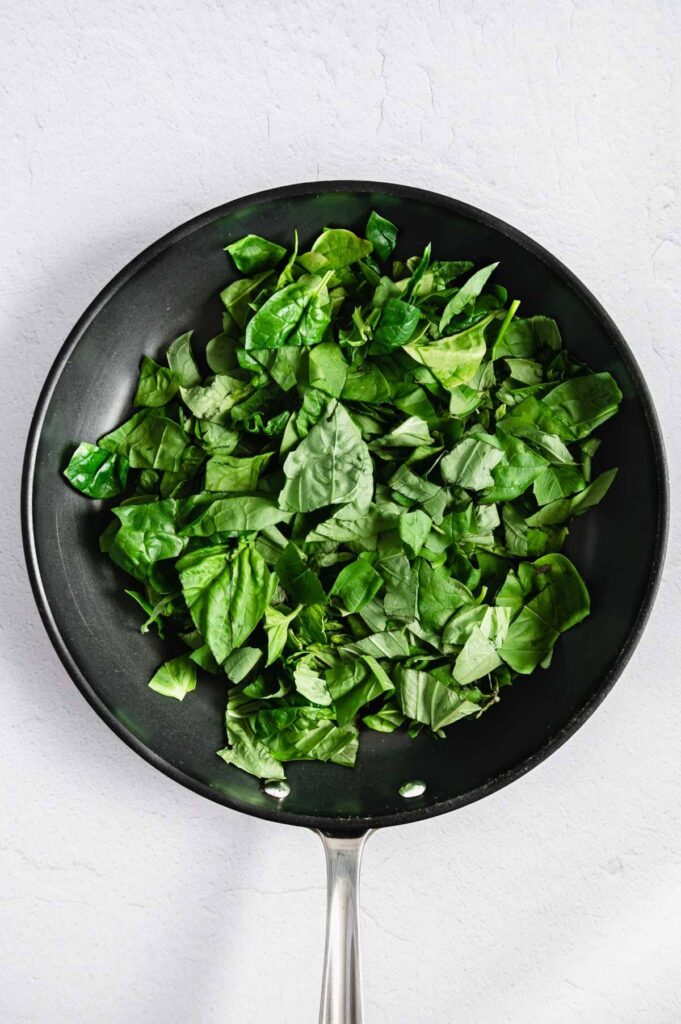 Fresh spinach and basil in a saucepan.