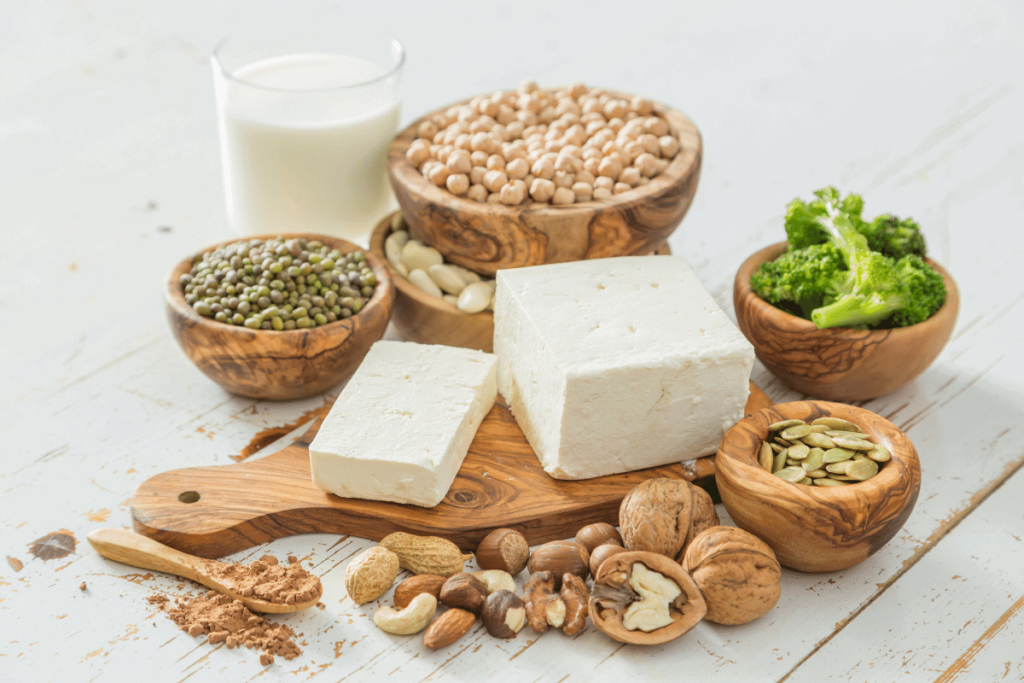 Different vegan protein sources - broccoli, tofu, beans, seeds, legumes, and nuts.