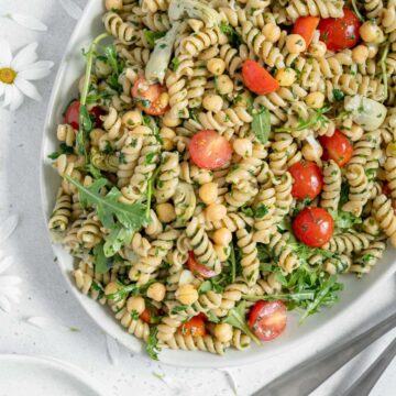 Overhead of a serving platter with vegan pesto pasta salad.