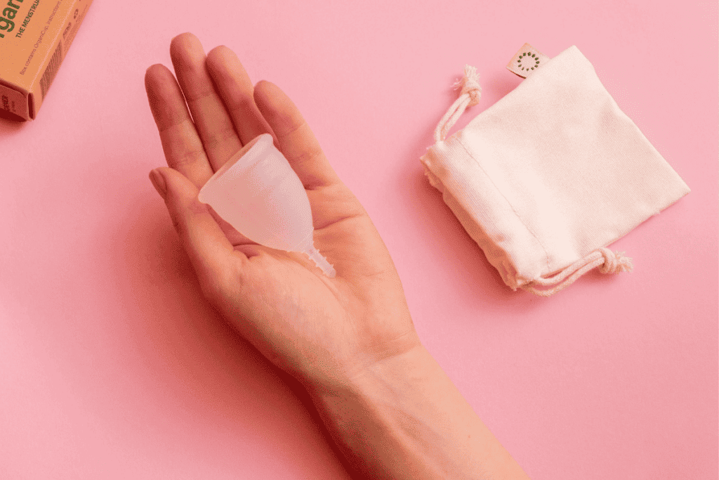A hand holding out a silicone menstrual cup.