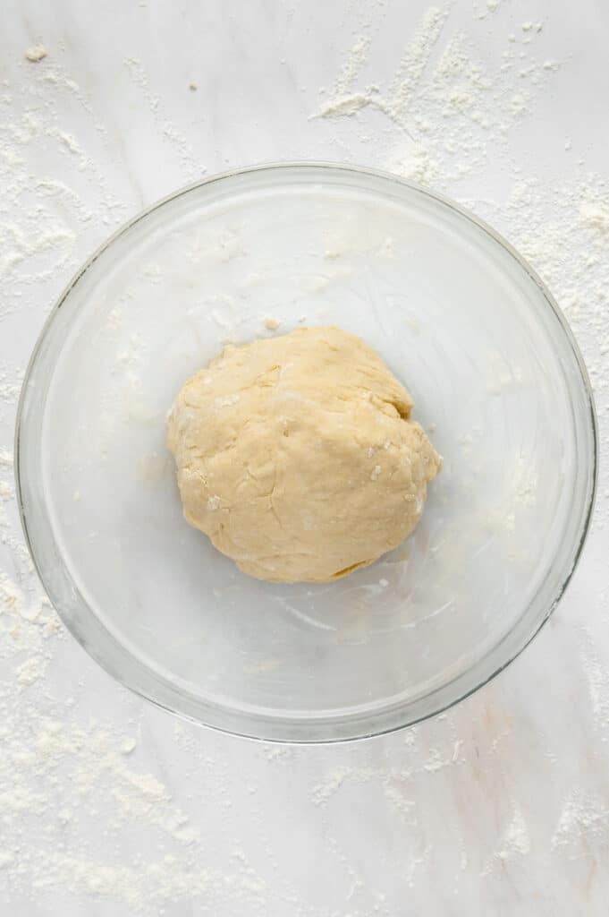 Kneaded cinnamon roll dough in a greased bowl.