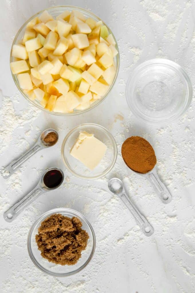 Ingredients to make sautéed apple filling in several glass bowls.