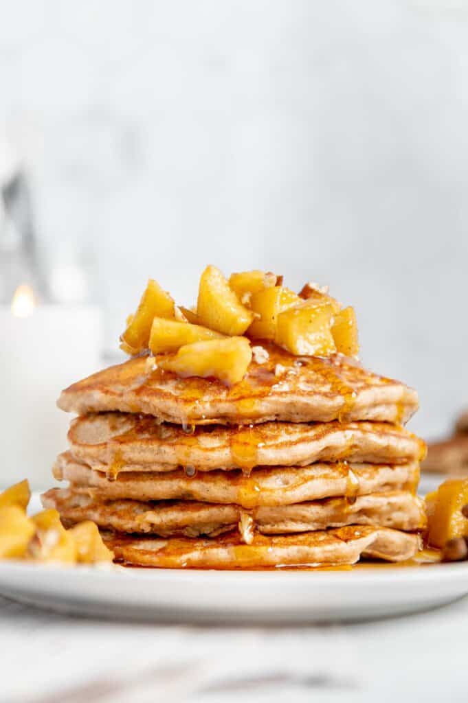 A stack of five vegan apple pancakes with sautéed apples on top.