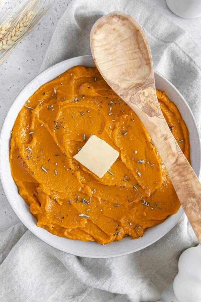 Vibrant mashed sweet potatoes with a slice of butter in the center.