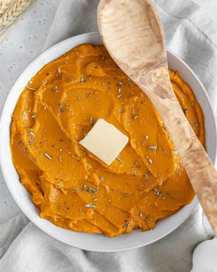 Vibrant mashed sweet potatoes with a slice of butter in the center.