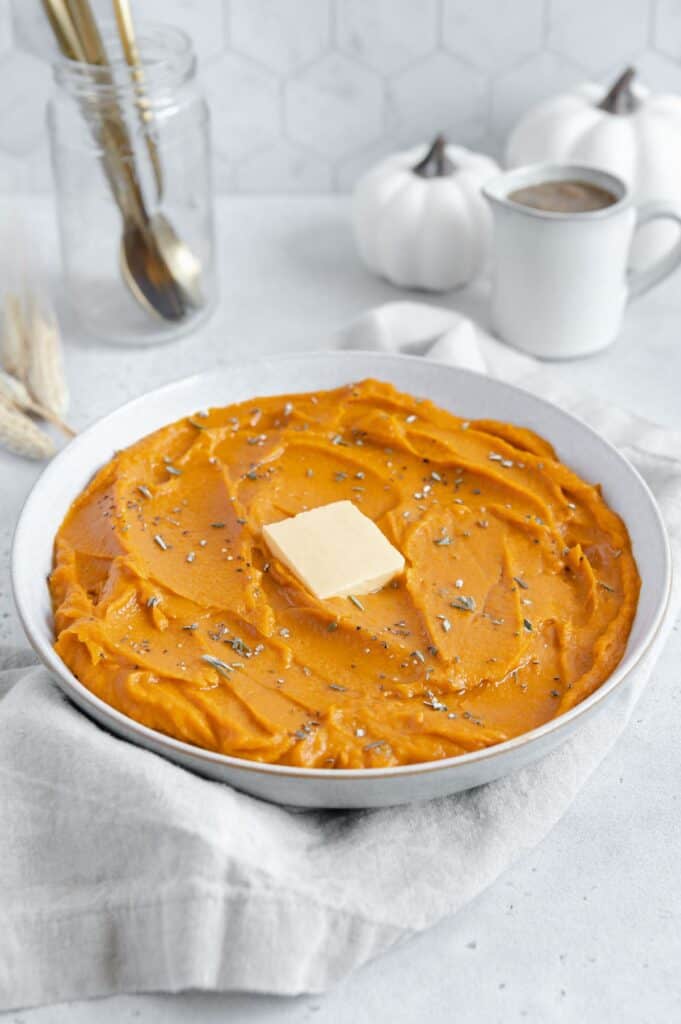Sweet potatoes surrounded by gravy and pumpkins.
