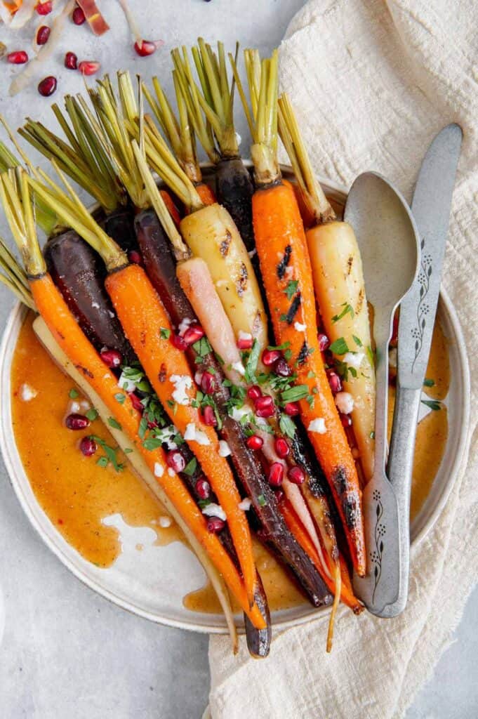 Plated maple roasted carrots with a serving spoon and knife.