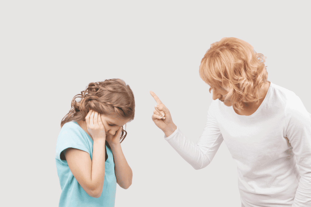 A women disciplining a little girl who is covering her ears.